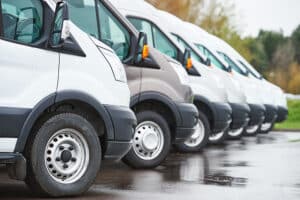 Commercial fleet of vans parked in a row on wet pavement, representing vehicle security and asset protection solutions for Norfolk businesses.